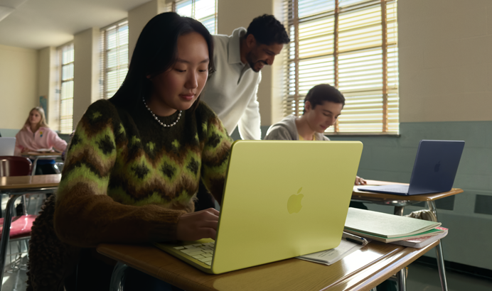 Estudante a usar o MacBook Neo na cor cítrico, desligado da tomada a ser usado em contexto de sala de aula