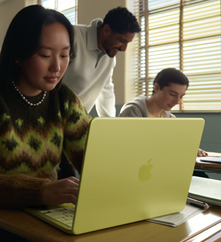 Estudante a usar o MacBook Neo na cor cítrico, desligado da tomada a ser usado em contexto de sala de aula