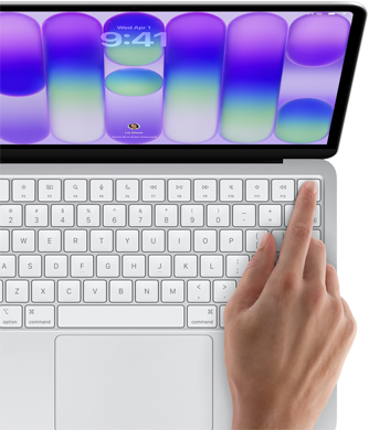 MacBook Neo na cor prateado, a mostrar o ecrã de início de sessão, o dedo de uma pessoa no sensor Touch ID no canto superior direito do teclado