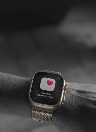Pessoa a usar o Apple Watch Ultra 3 no pulso, com aviso de possível hipertensão arterial apresentado no ecrã