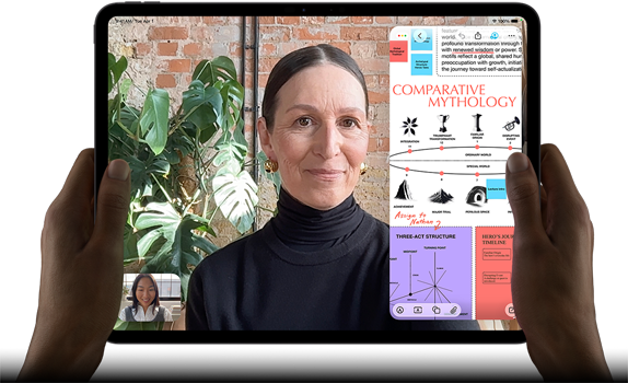 Vista frontal do iPad Pro, preto sideral, colocado na horizontal, ecrã com moldura preta e cantos arredondados, mãos a segurar os lados esquerdo e direito, ecrã apresenta uma conversa no FaceTime com tradução em tempo real e uma app educativa com uma apresentação intitulada 